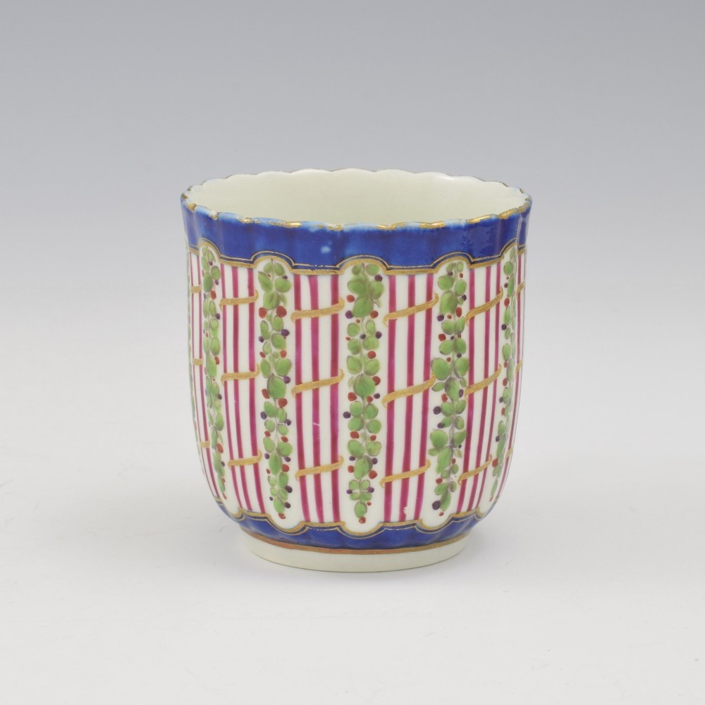 An 18th-century soft-paste porcelain coffee cup and saucer with fluted edges, featuring a cobalt blue border, gilt highlights, and a painted green hop trellis pattern. View VI
