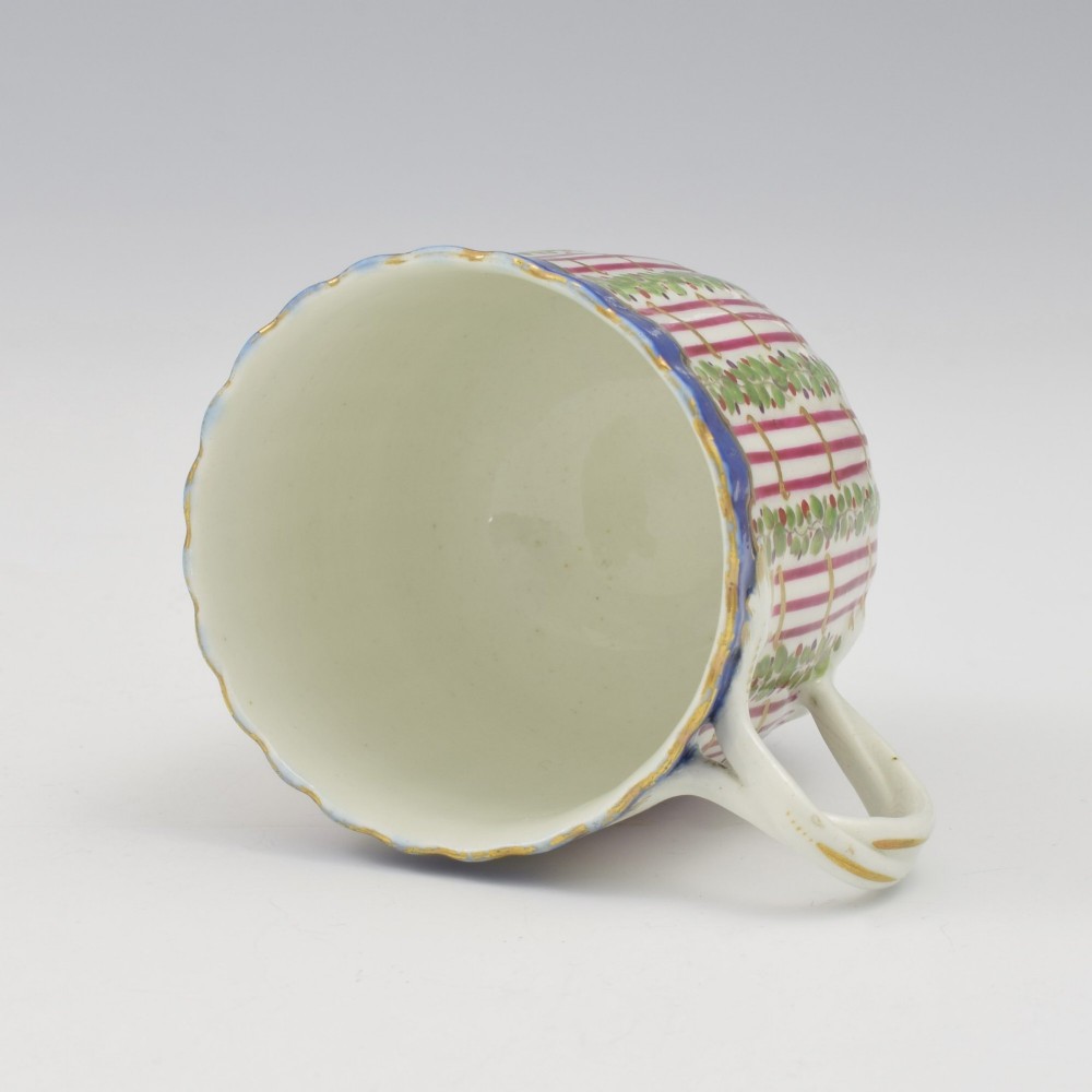 An 18th-century soft-paste porcelain coffee cup and saucer with fluted edges, featuring a cobalt blue border, gilt highlights, and a painted green hop trellis pattern. View VII