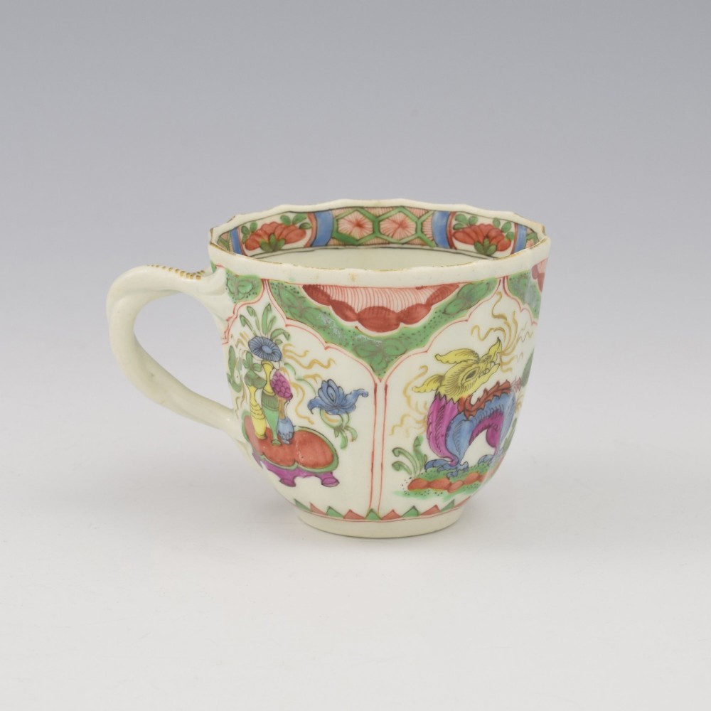 An 18th-century fluted soft-paste porcelain coffee cup with hand-painted Chinoiserie dragon motifs and a looped handle.