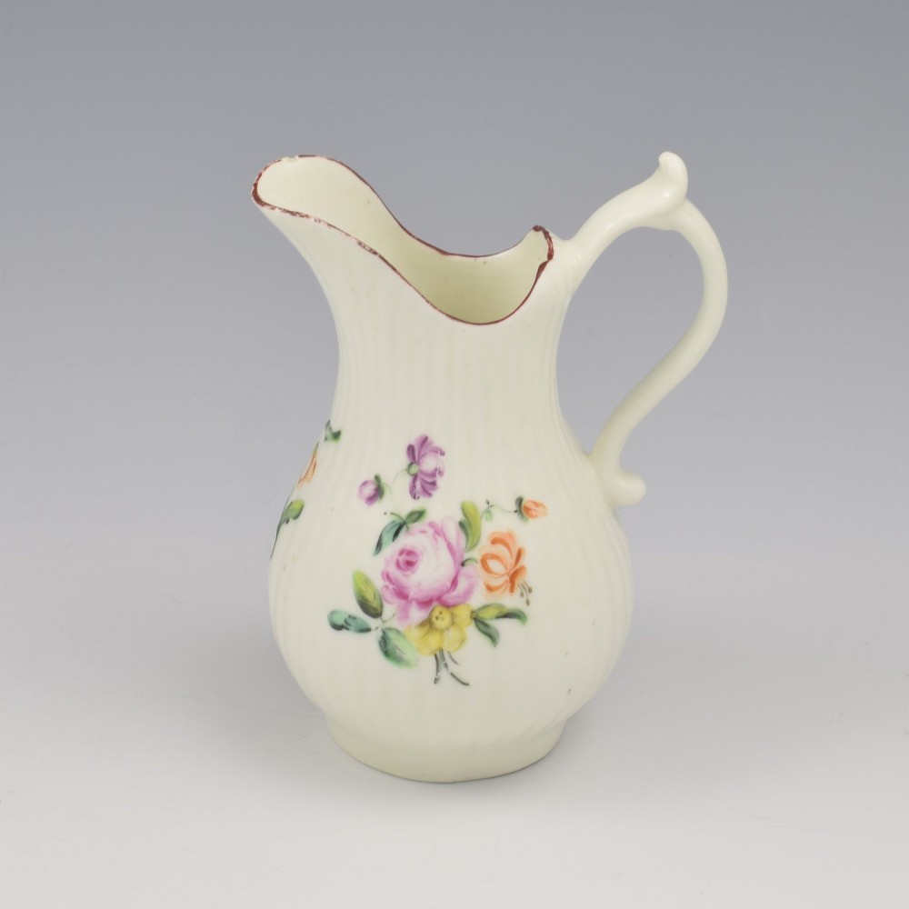 An eighteenth-century English soft-paste porcelain cream jug with vertical fluting, hand-painted floral motifs, and a looped handle. View II