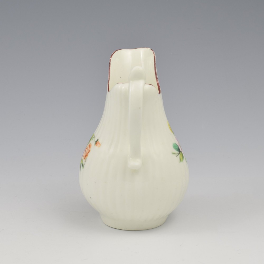 An eighteenth-century English soft-paste porcelain cream jug with vertical fluting, hand-painted floral motifs, and a looped handle. View V