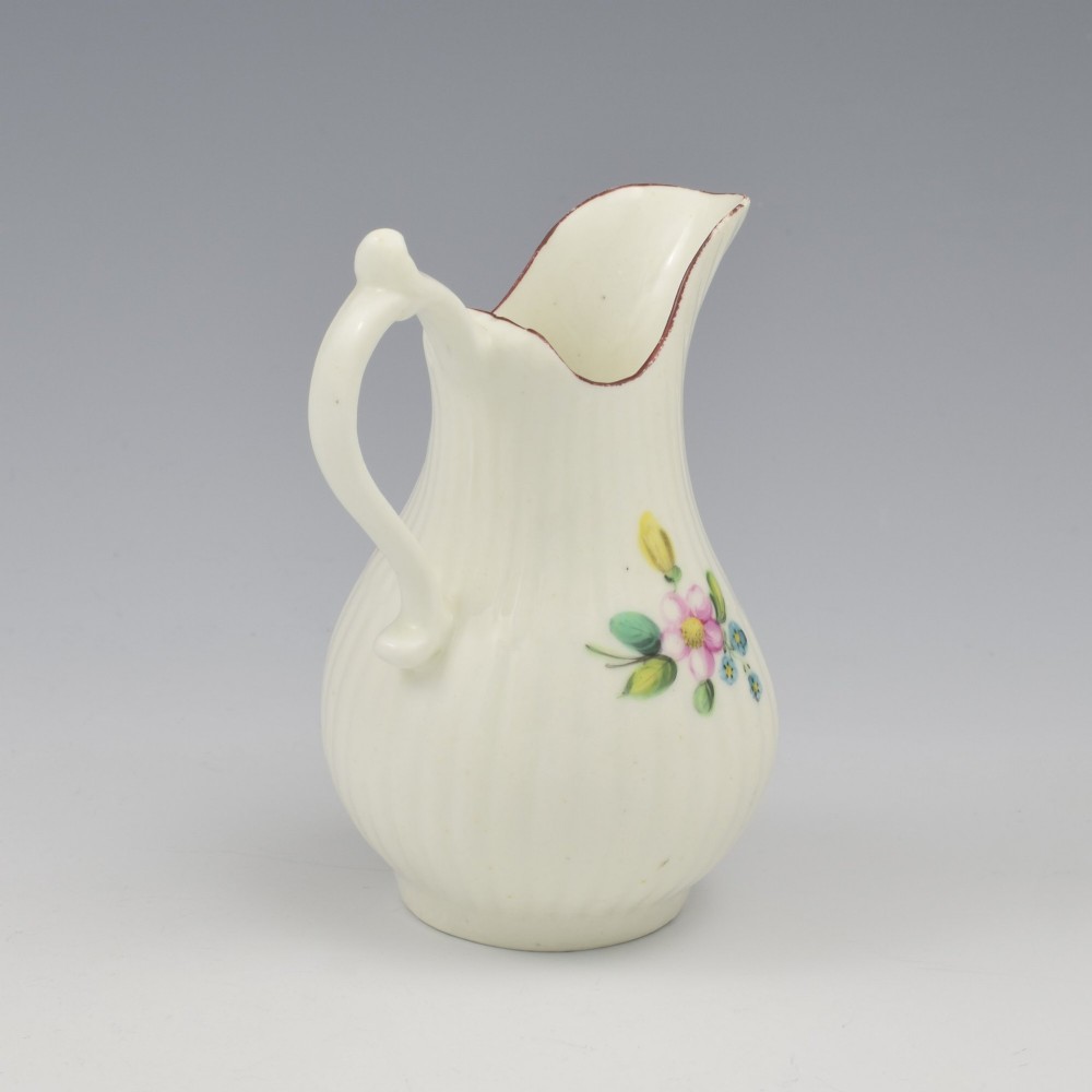 An eighteenth-century English soft-paste porcelain cream jug with vertical fluting, hand-painted floral motifs, and a looped handle. View VI