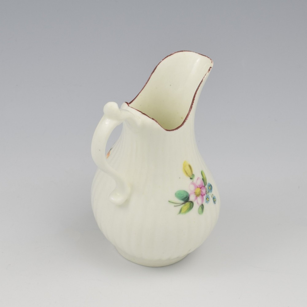 An eighteenth-century English soft-paste porcelain cream jug with vertical fluting, hand-painted floral motifs, and a looped handle. View VII
