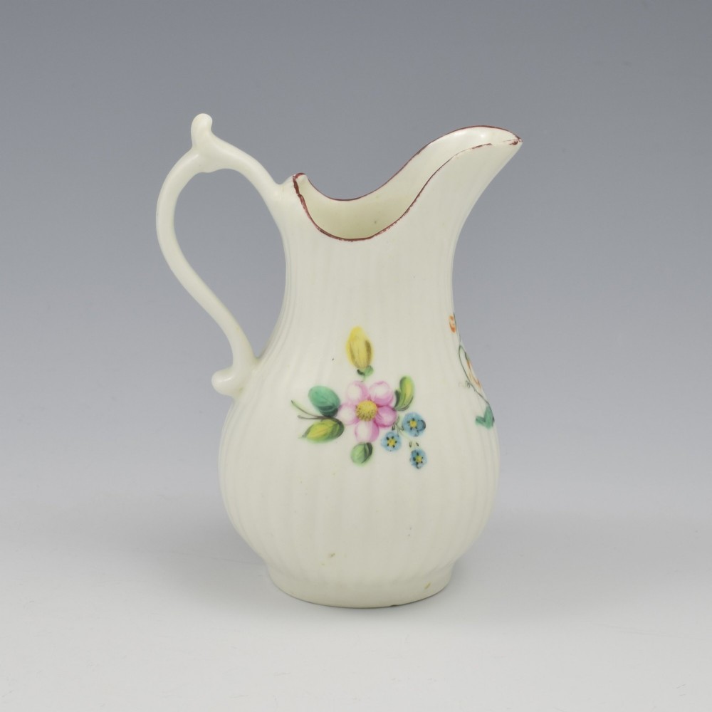 An eighteenth-century English soft-paste porcelain cream jug with vertical fluting, hand-painted floral motifs, and a looped handle. View VIII