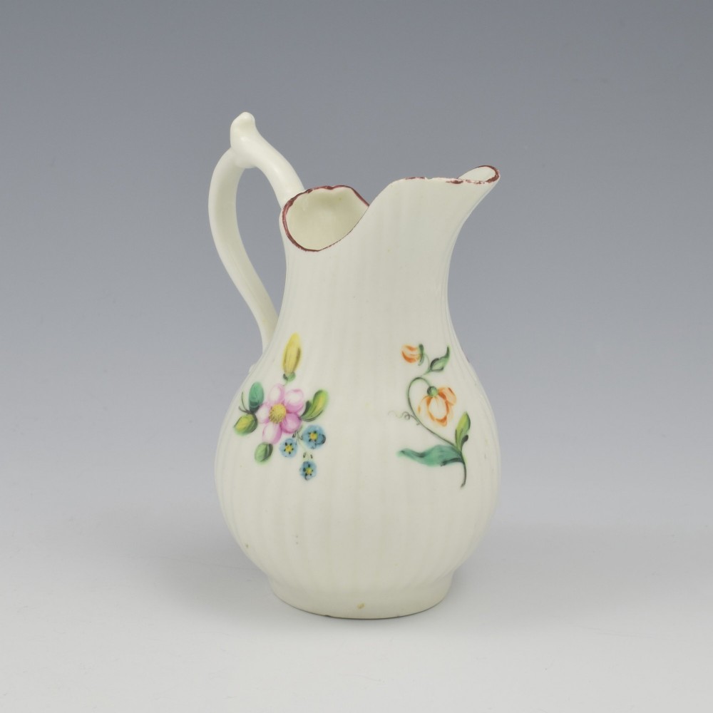 An eighteenth-century English soft-paste porcelain cream jug with vertical fluting, hand-painted floral motifs, and a looped handle. View IX