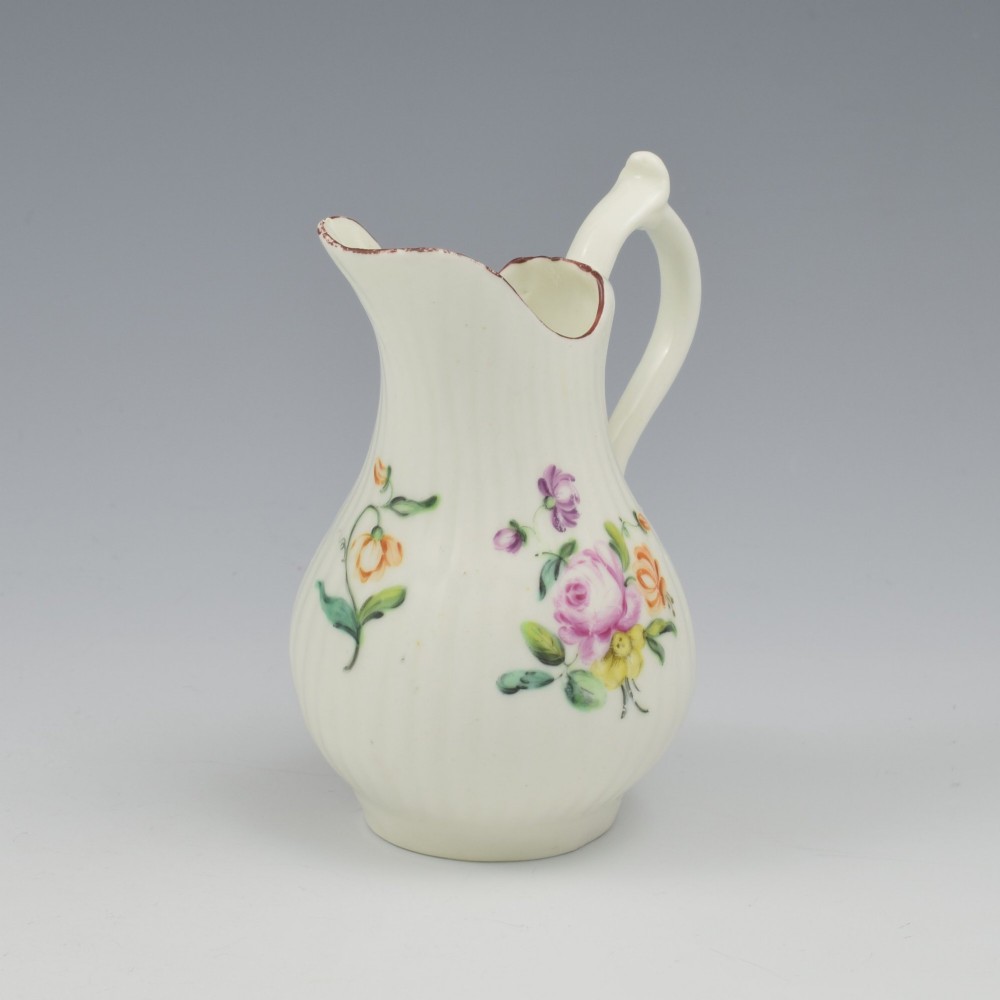 An eighteenth-century English soft-paste porcelain cream jug with vertical fluting, hand-painted floral motifs, and a looped handle. View XI