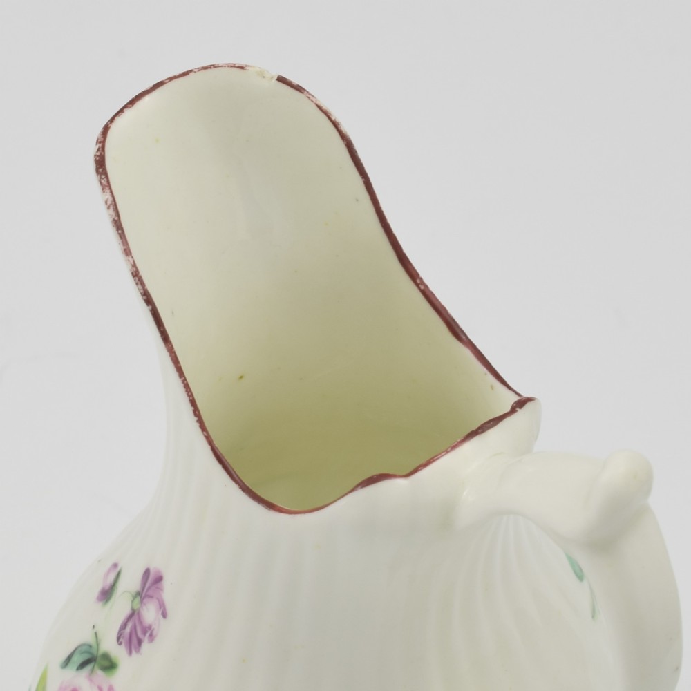 An eighteenth-century English soft-paste porcelain cream jug with vertical fluting, hand-painted floral motifs, and a looped handle. View XII