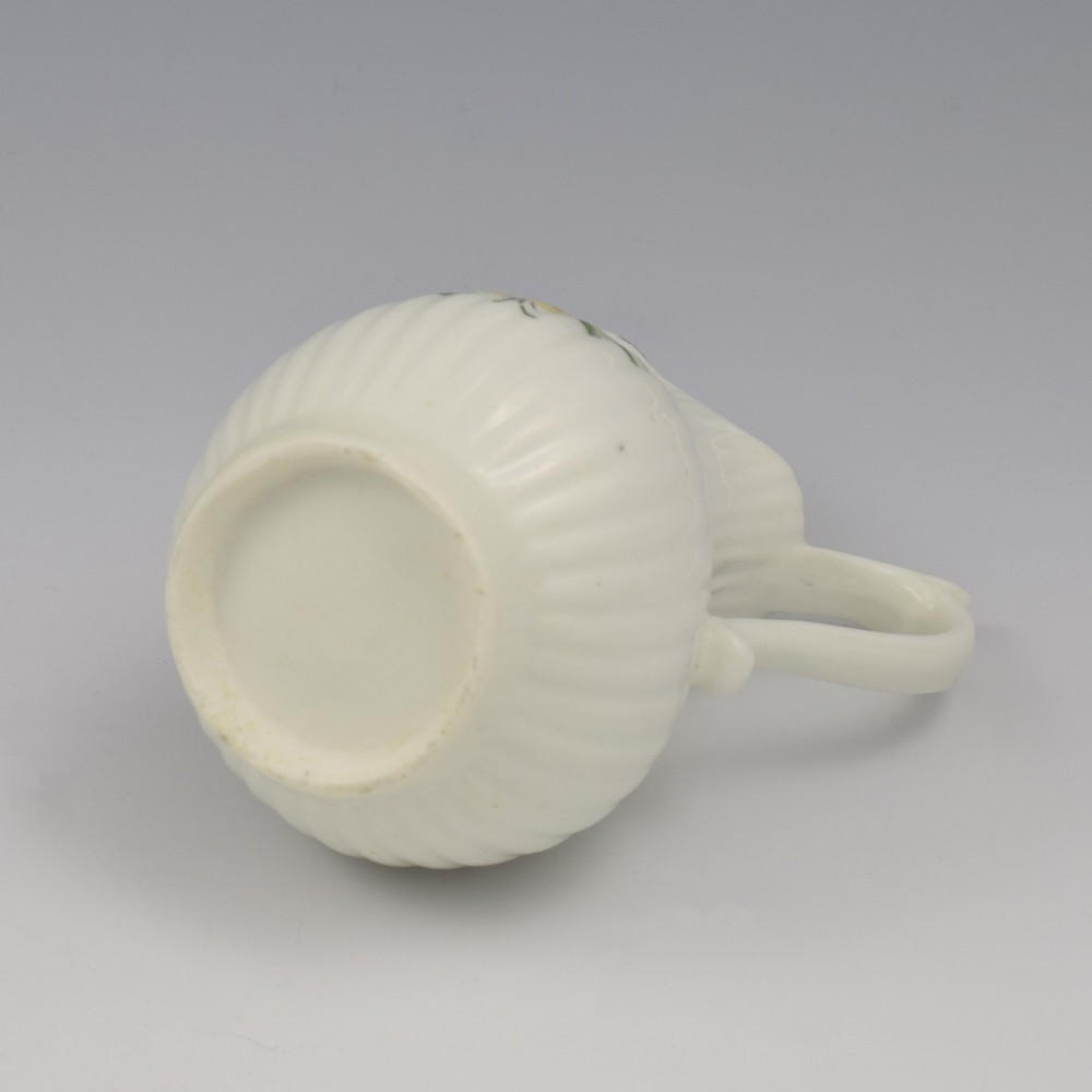 An eighteenth-century English soft-paste porcelain cream jug with vertical fluting, hand-painted floral motifs, and a looped handle. View XIV