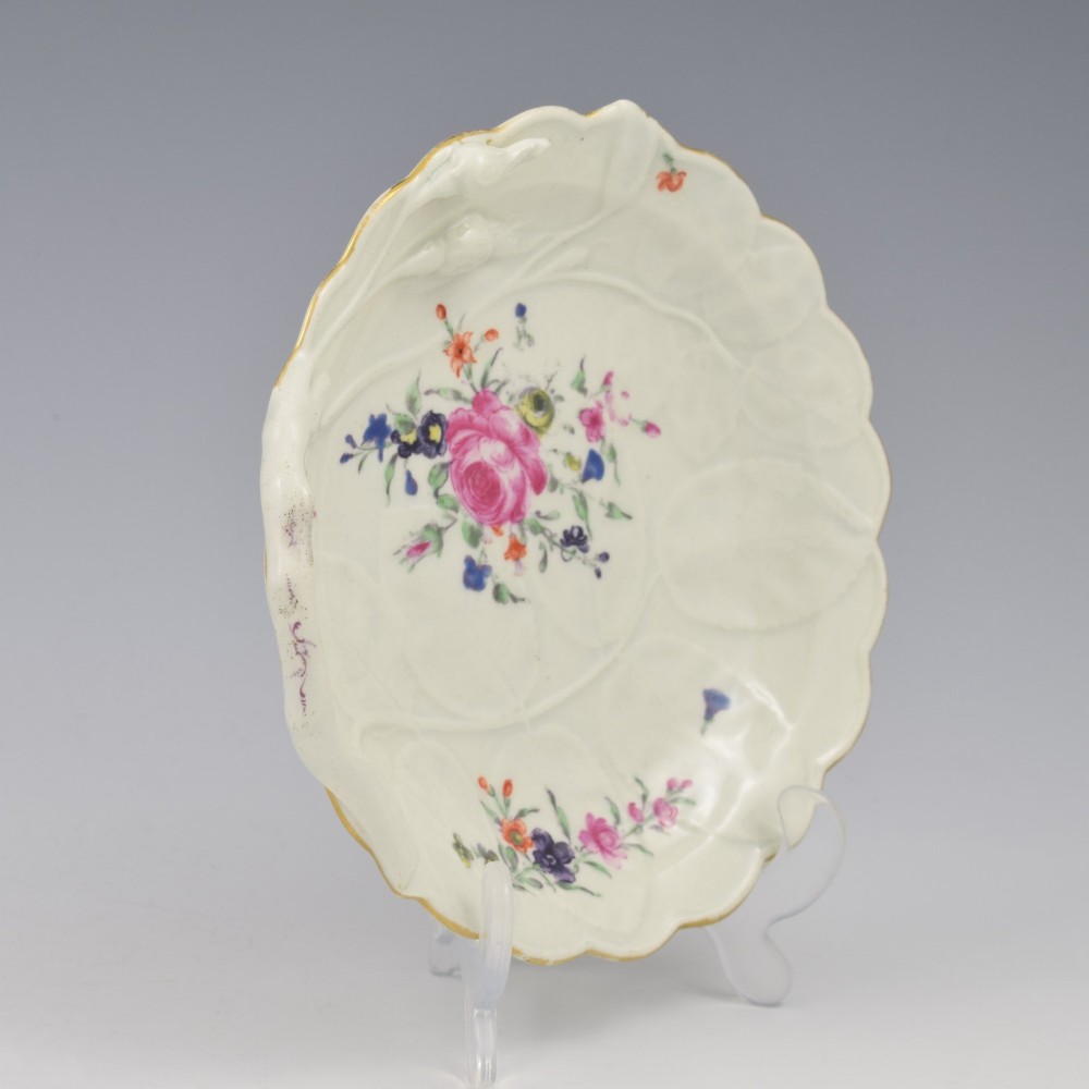An 18th-century Worcester soft-paste porcelain sweetmeat dish featuring relief-moulded rose leaves, a branch handle, multi-coloured hand-painted floral sprays, and a gilded rim. View V