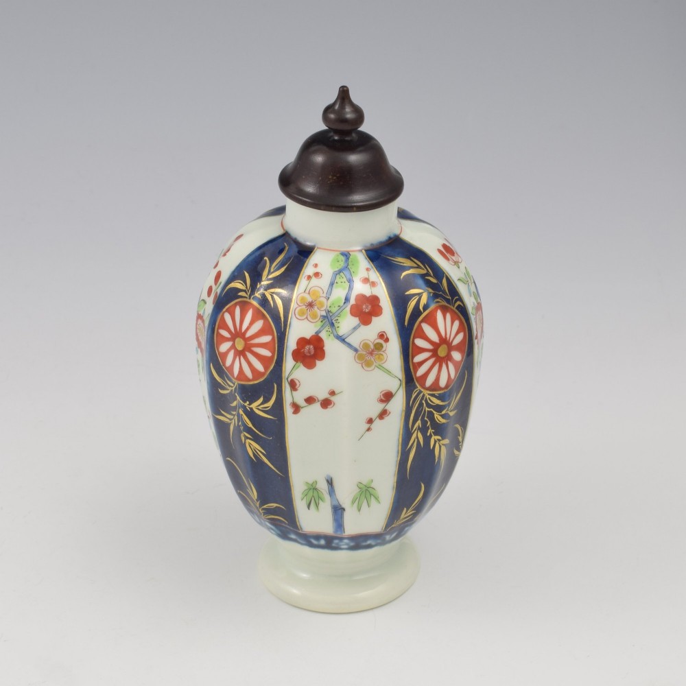 A First Period Worcester soft-paste porcelain tea canister decorated with cobalt blue panels, gilt scrolls, and polychrome floral reserves. View IX