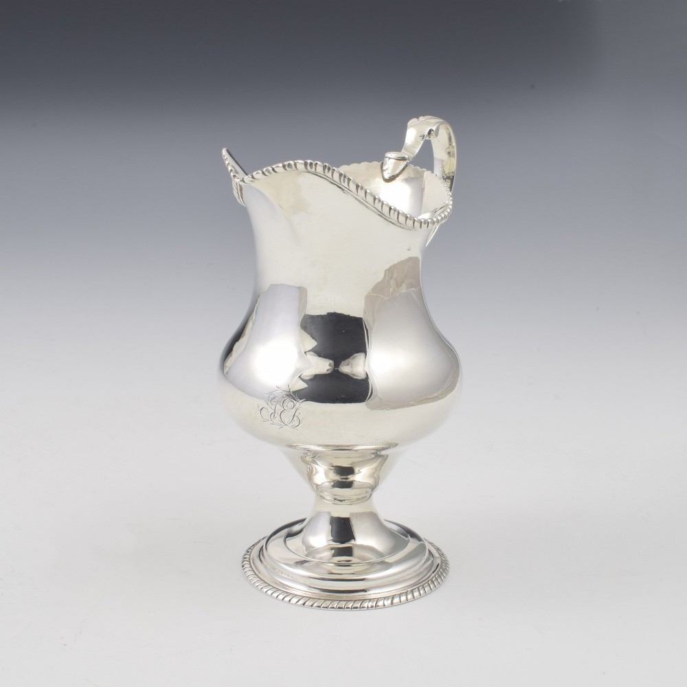 A Georgian sterling silver milk jug featuring a baluster body, pedestal foot, beaded rim, and double-scroll handle. View II
