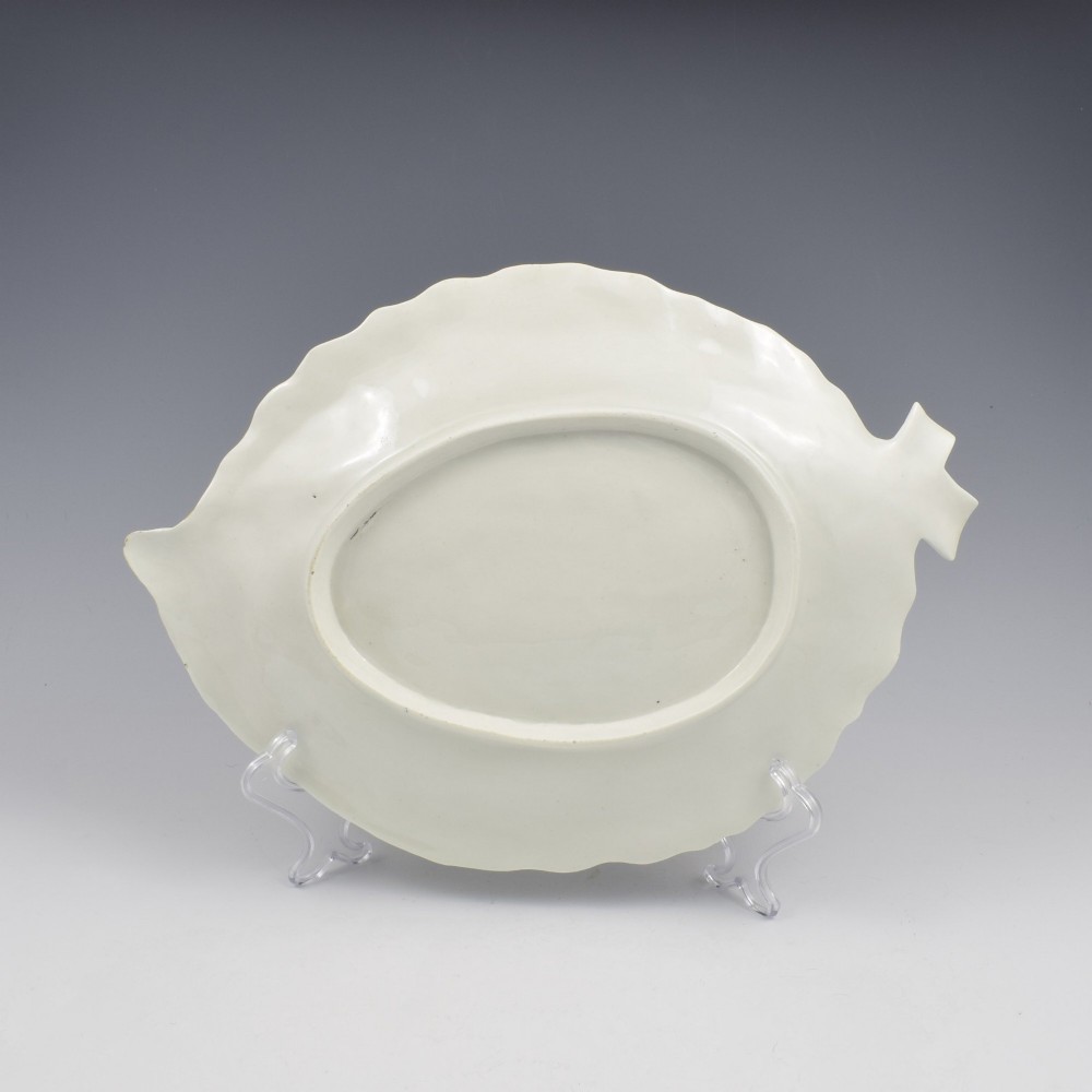 An eighteenth-century leaf-moulded soft-paste porcelain dish featuring central hand-painted fancy birds, surrounding butterflies, a pink stalk handle, and a gilded edge. View IX