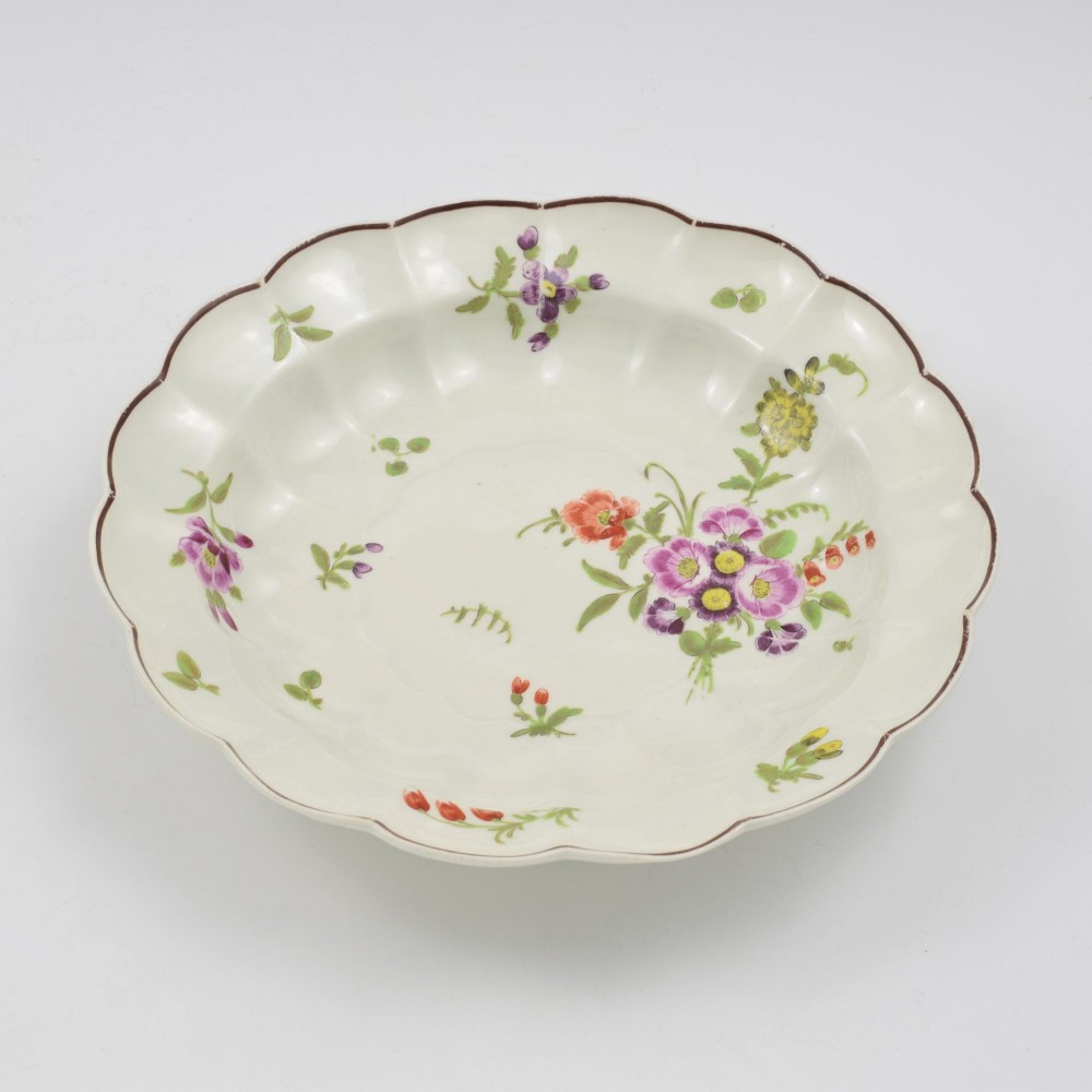 An 18th-century lobed soft-paste porcelain plate decorated with hand-painted polychrome floral sprays and a brown line rim. View VIII