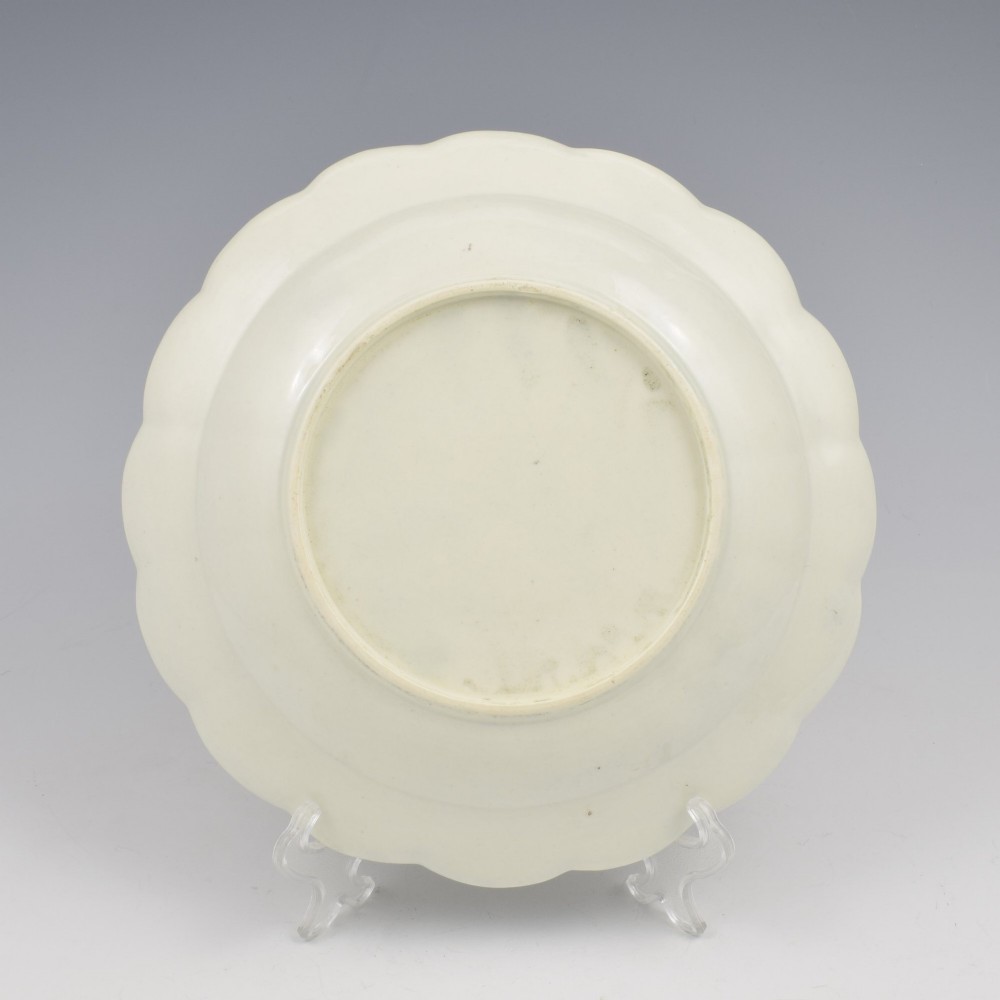 An 18th-century lobed soft-paste porcelain plate decorated with hand-painted polychrome floral sprays and a brown line rim. View X