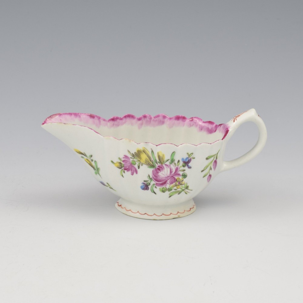 An eighteenth-century Bow soft-paste porcelain fluted sauce boat with hand-painted floral sprigs and a magenta feathered rim.