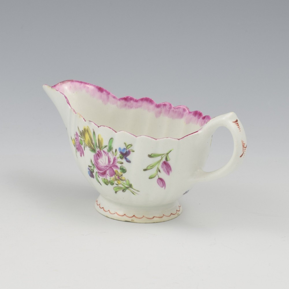 An eighteenth-century Bow soft-paste porcelain fluted sauce boat with hand-painted floral sprigs and a magenta feathered rim. View X