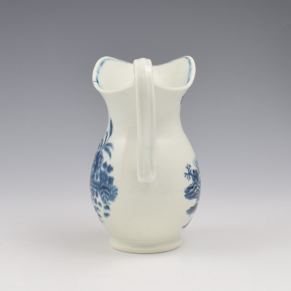 An 18th-century blue and white Worcester porcelain milk ewer featuring a flared spout, loop handle, and hand-painted floral motifs. View VII
