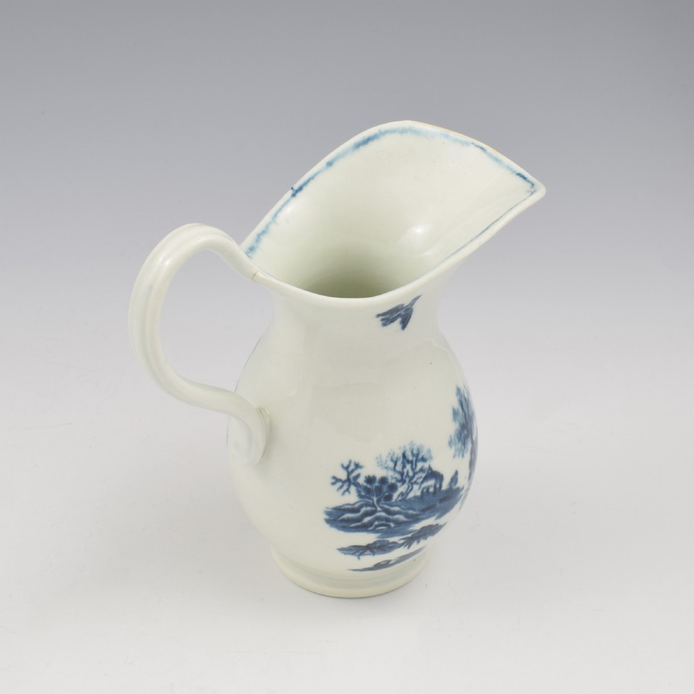 An 18th-century blue and white Worcester porcelain milk ewer featuring a flared spout, loop handle, and hand-painted floral motifs. View XI