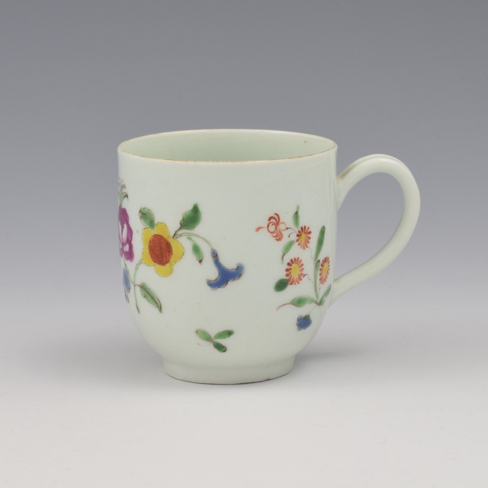 An 18th-century white porcelain coffee cup painted with polychrome floral sprays and featuring a single loop handle.