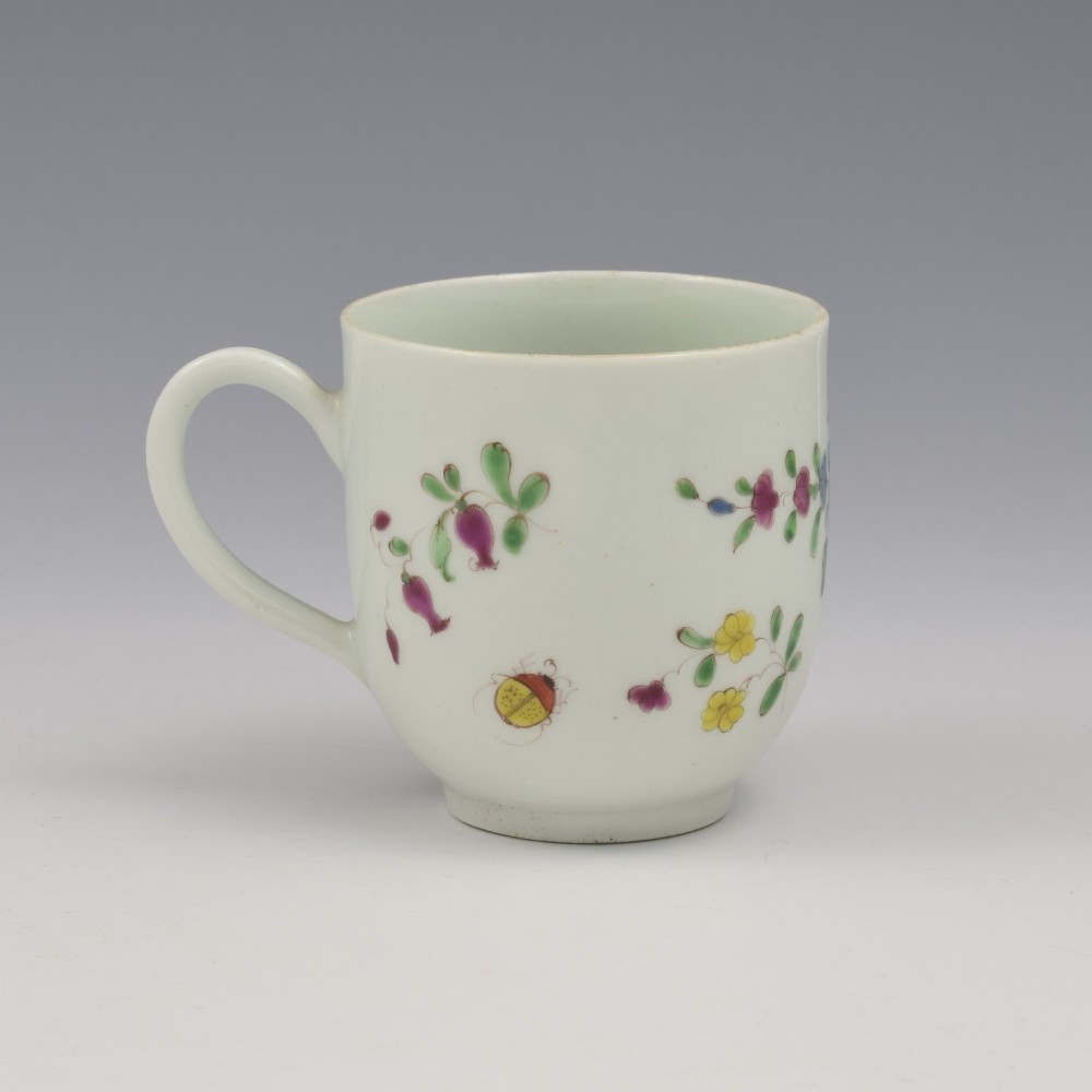 An 18th-century white porcelain coffee cup painted with polychrome floral sprays and featuring a single loop handle. View V