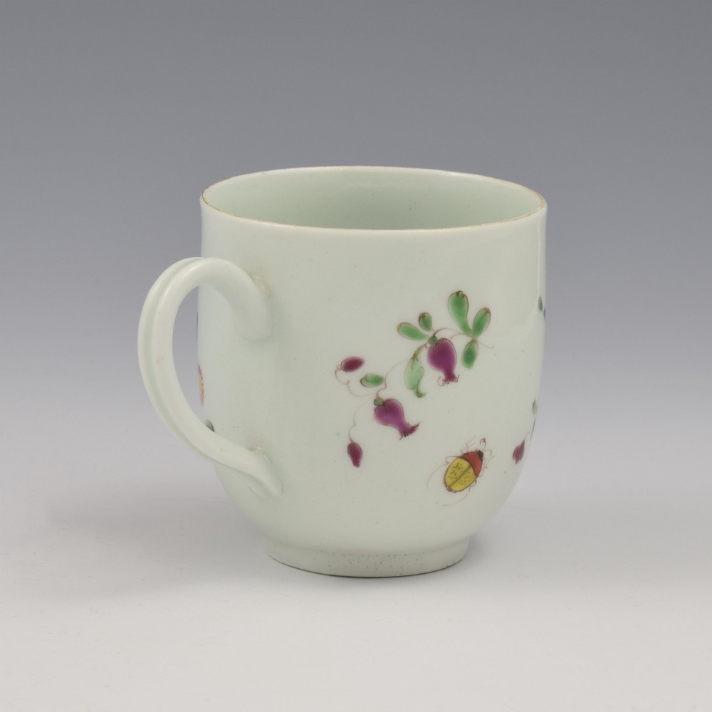 An 18th-century white porcelain coffee cup painted with polychrome floral sprays and featuring a single loop handle. View VI