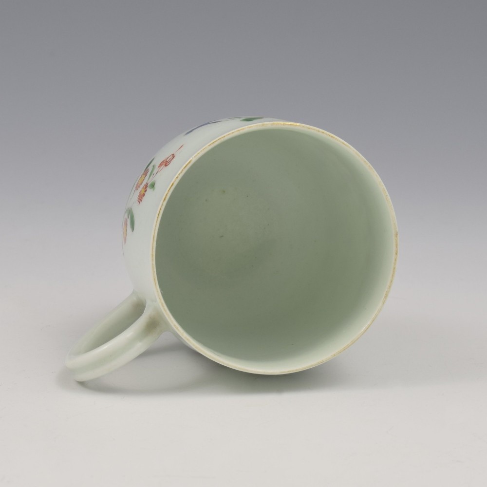 An 18th-century white porcelain coffee cup painted with polychrome floral sprays and featuring a single loop handle. View IX
