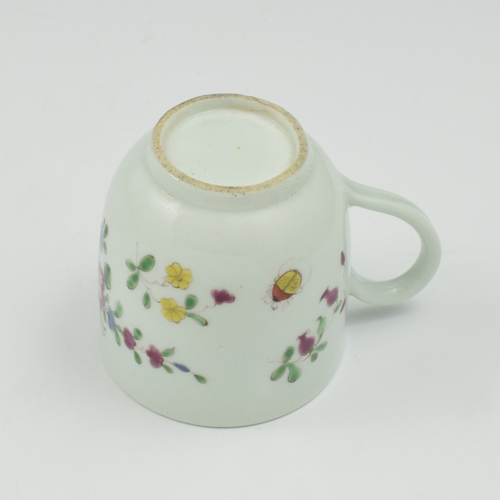 An 18th-century white porcelain coffee cup painted with polychrome floral sprays and featuring a single loop handle. View X