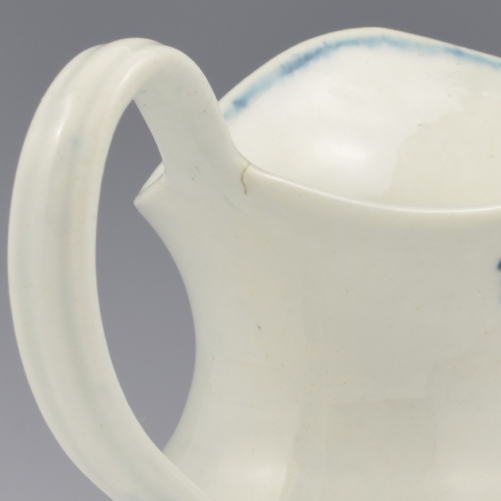 An 18th-century blue and white Worcester porcelain milk ewer featuring a flared spout, loop handle, and hand-painted floral motifs. View XV
