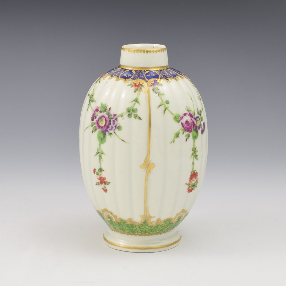 An 18th-century fluted white porcelain tea canister decorated with hand-painted floral swags, gilded trim, and a cobalt blue pattern around the neck. View III
