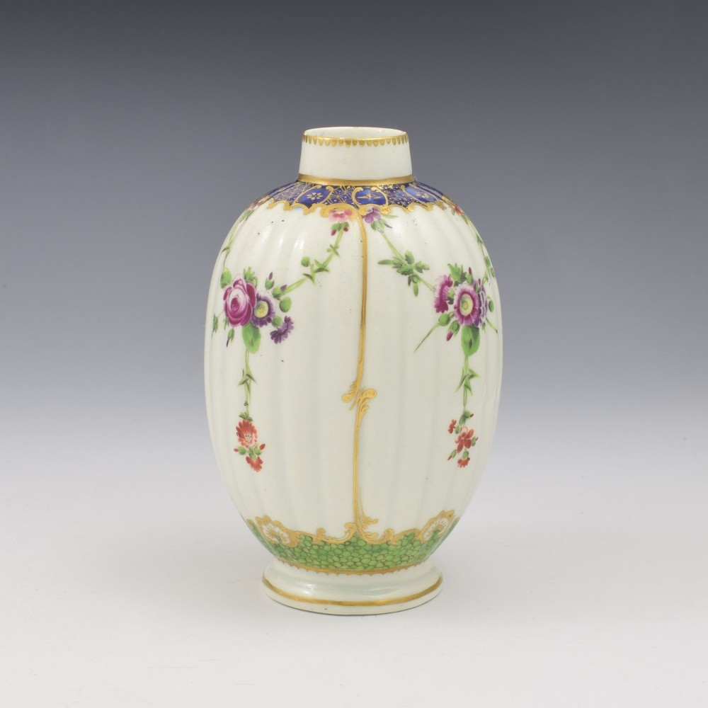 An 18th-century fluted white porcelain tea canister decorated with hand-painted floral swags, gilded trim, and a cobalt blue pattern around the neck. View IV