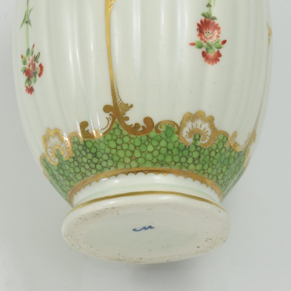 An 18th-century fluted white porcelain tea canister decorated with hand-painted floral swags, gilded trim, and a cobalt blue pattern around the neck. View VII