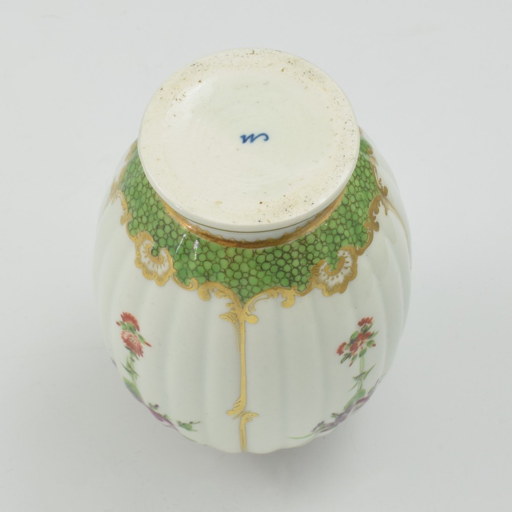 An 18th-century fluted white porcelain tea canister decorated with hand-painted floral swags, gilded trim, and a cobalt blue pattern around the neck. View VIII