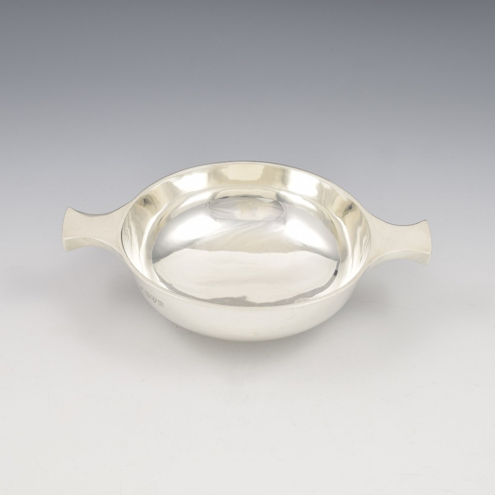 A circular Edwardian sterling silver quaich with a plain polished interior and two flat side handles.