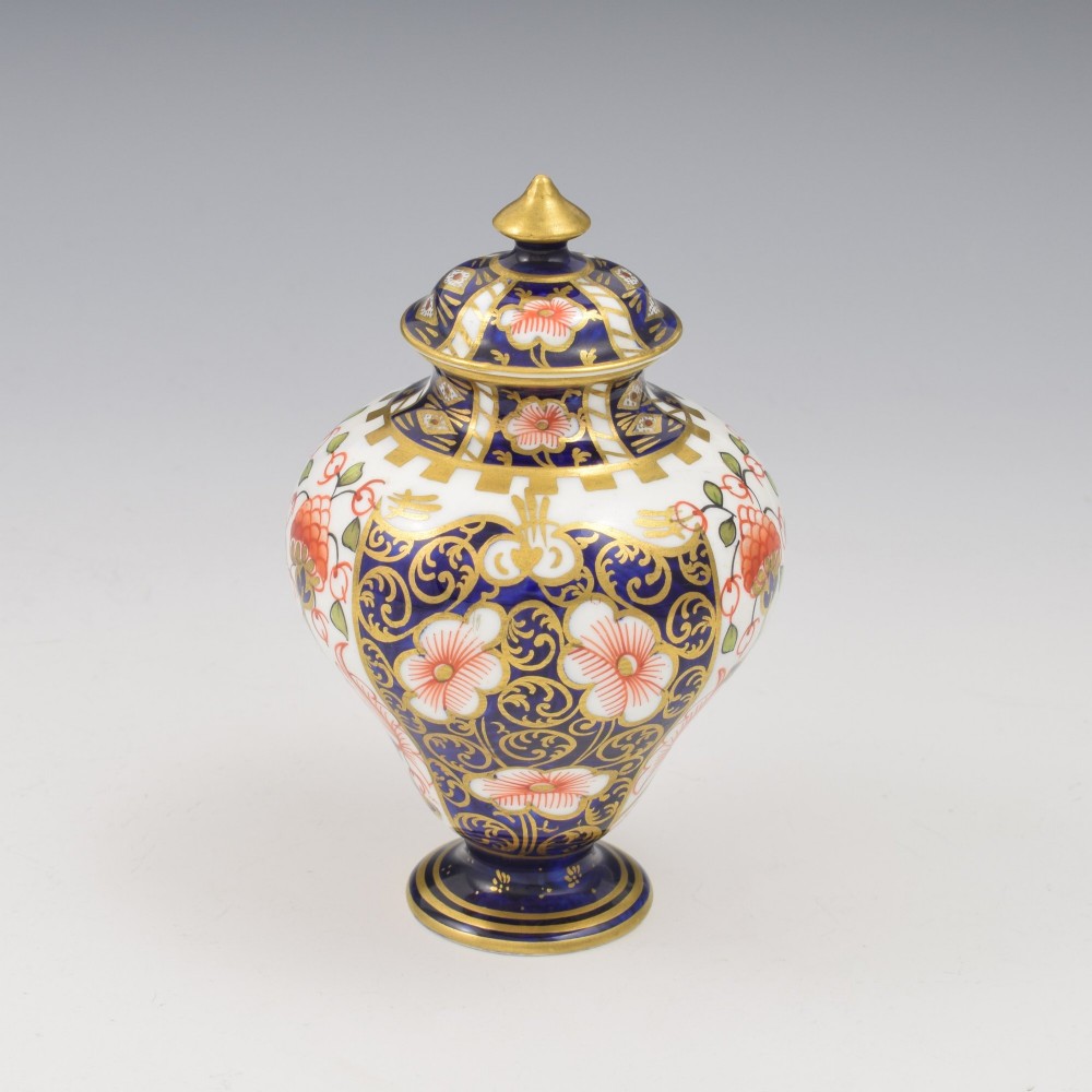 A baluster-shaped porcelain miniature vase and matching domed lid decorated with a cobalt blue, iron red, and gilt Imari pattern. View II