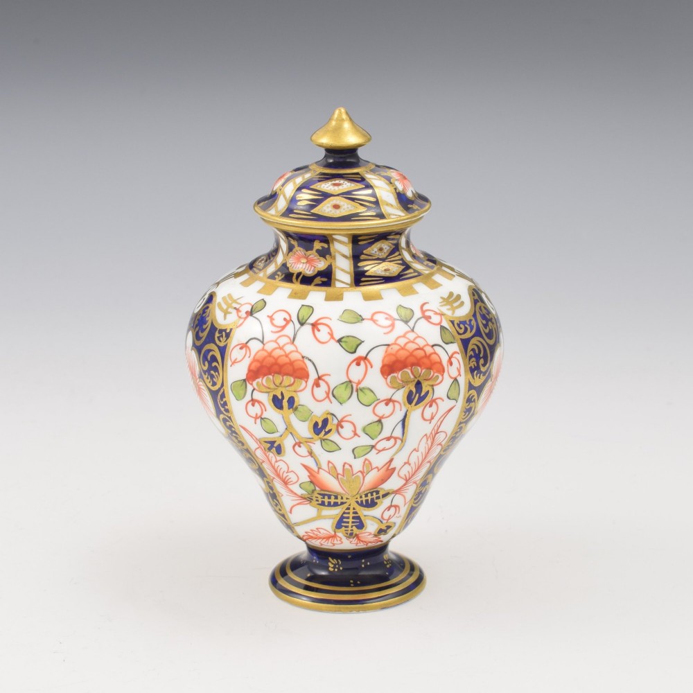 A baluster-shaped porcelain miniature vase and matching domed lid decorated with a cobalt blue, iron red, and gilt Imari pattern. View VI