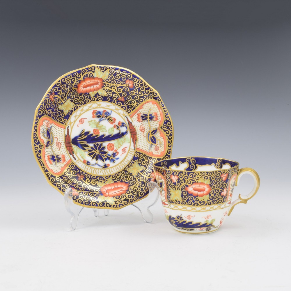 An Edwardian Royal Crown Derby porcelain coffee cup and matching saucer decorated in a rich cobalt blue, iron red, and gilt Imari pattern.