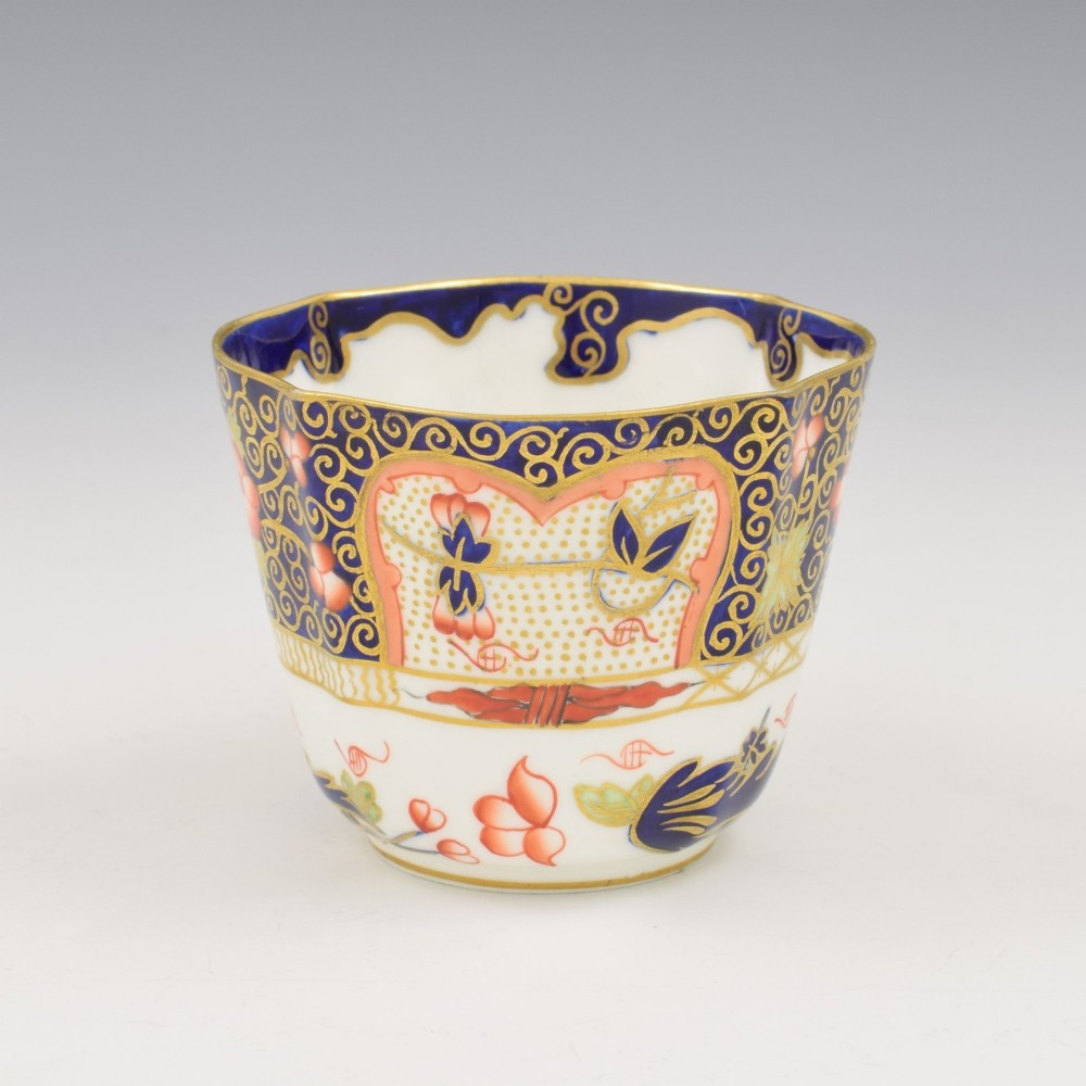 An Edwardian Royal Crown Derby porcelain coffee cup and matching saucer decorated in a rich cobalt blue, iron red, and gilt Imari pattern. View IV