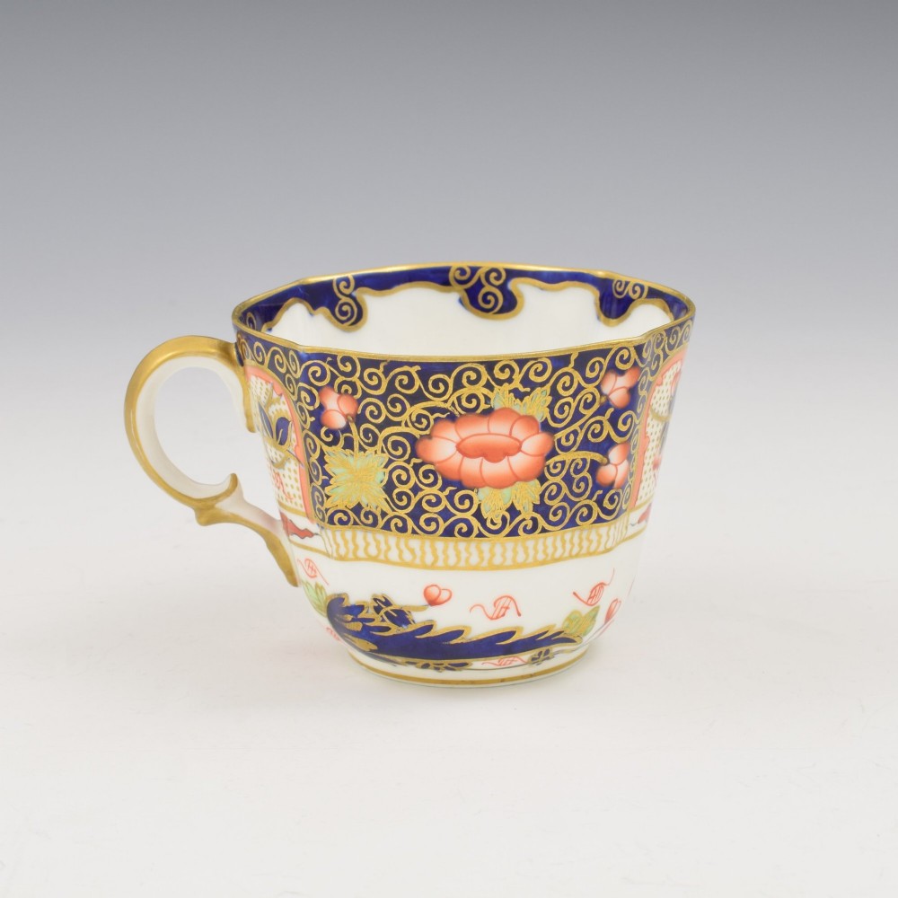 An Edwardian Royal Crown Derby porcelain coffee cup and matching saucer decorated in a rich cobalt blue, iron red, and gilt Imari pattern. View V