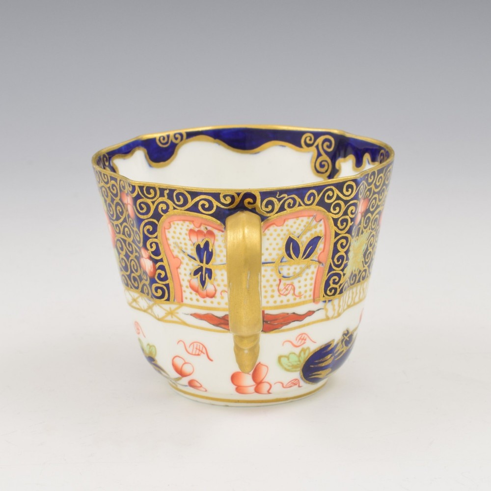 An Edwardian Royal Crown Derby porcelain coffee cup and matching saucer decorated in a rich cobalt blue, iron red, and gilt Imari pattern. View VI