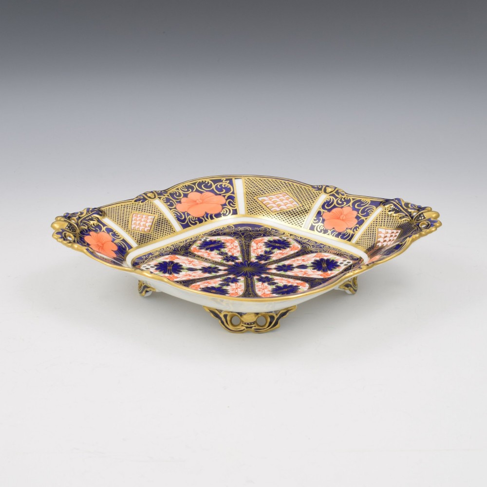 A shallow hexagonal bone china dish decorated in rich cobalt blue, iron red, and gold gilding, featuring pierced side handles and a footed base. View II