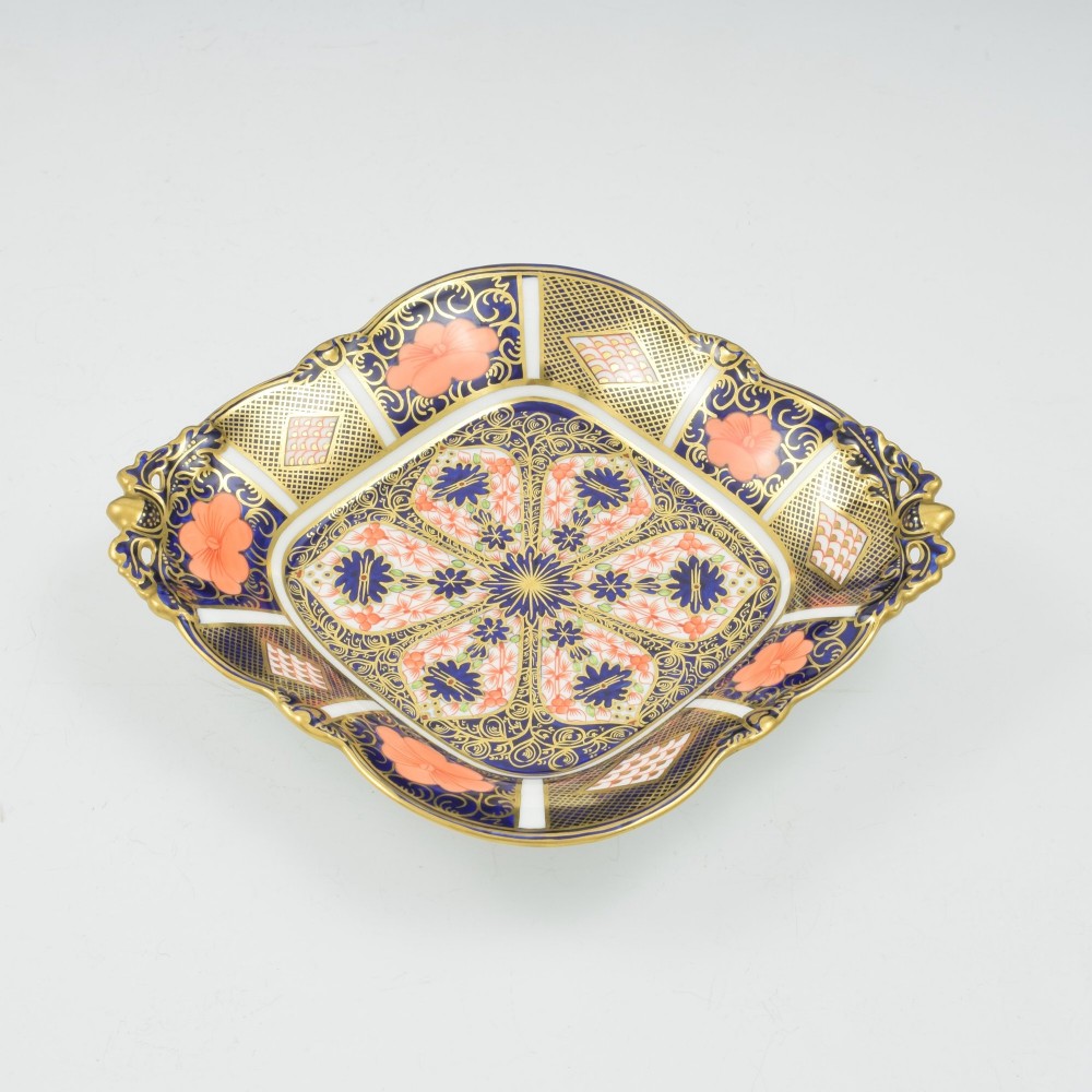 A shallow hexagonal bone china dish decorated in rich cobalt blue, iron red, and gold gilding, featuring pierced side handles and a footed base. View III