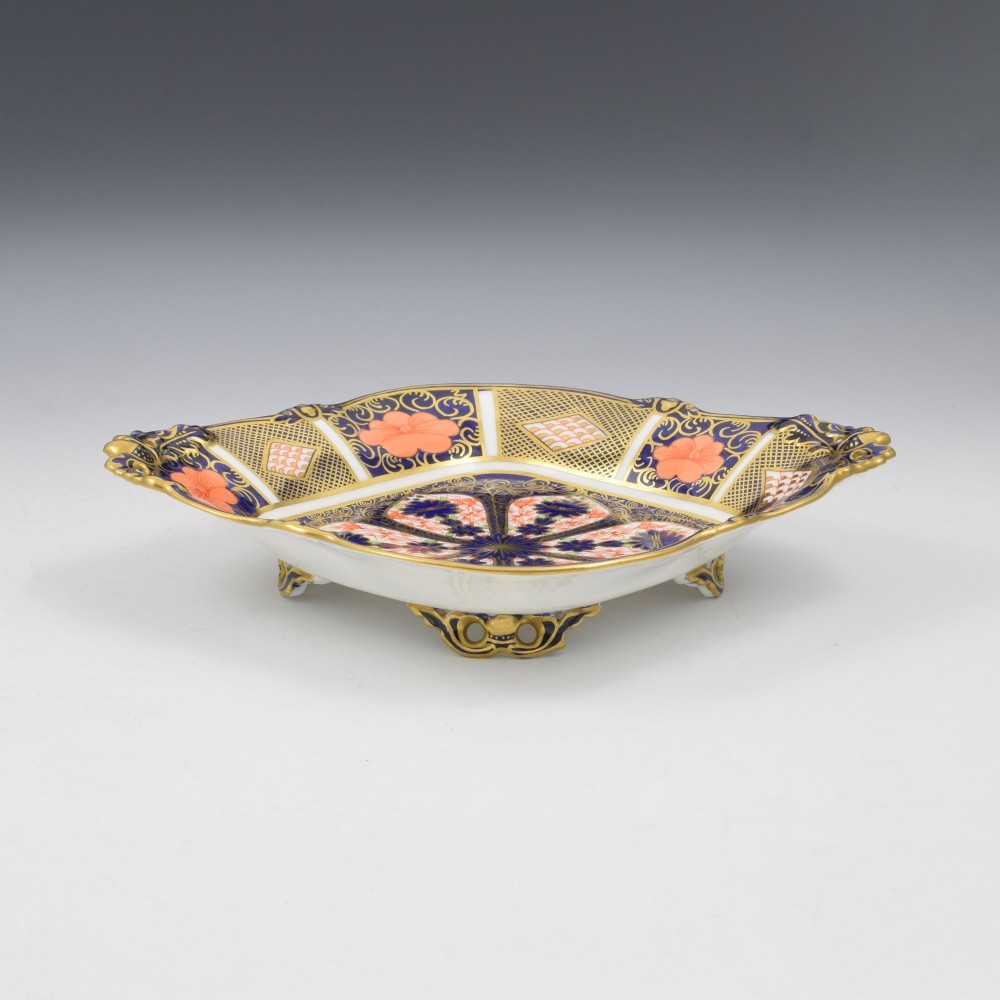 A shallow hexagonal bone china dish decorated in rich cobalt blue, iron red, and gold gilding, featuring pierced side handles and a footed base. View IV