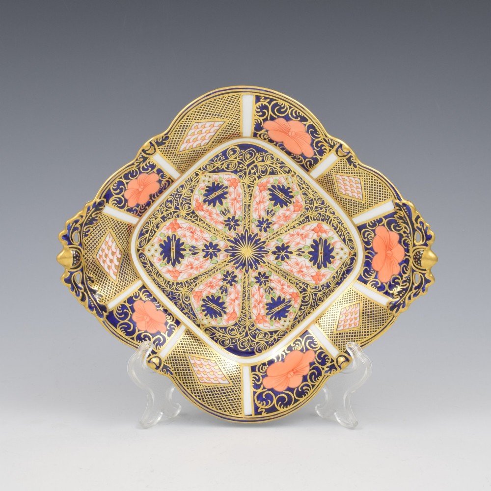 A shallow hexagonal bone china dish decorated in rich cobalt blue, iron red, and gold gilding, featuring pierced side handles and a footed base. View V