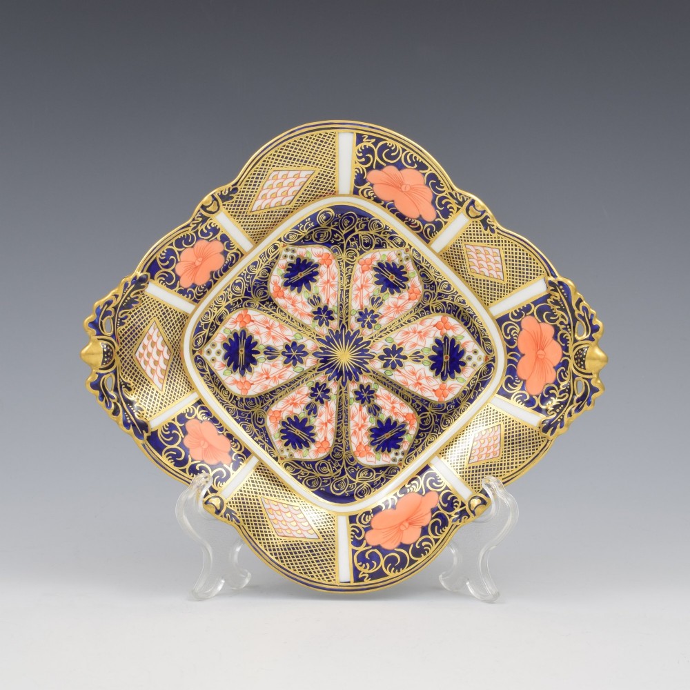 A shallow hexagonal bone china dish decorated in rich cobalt blue, iron red, and gold gilding, featuring pierced side handles and a footed base. View VI