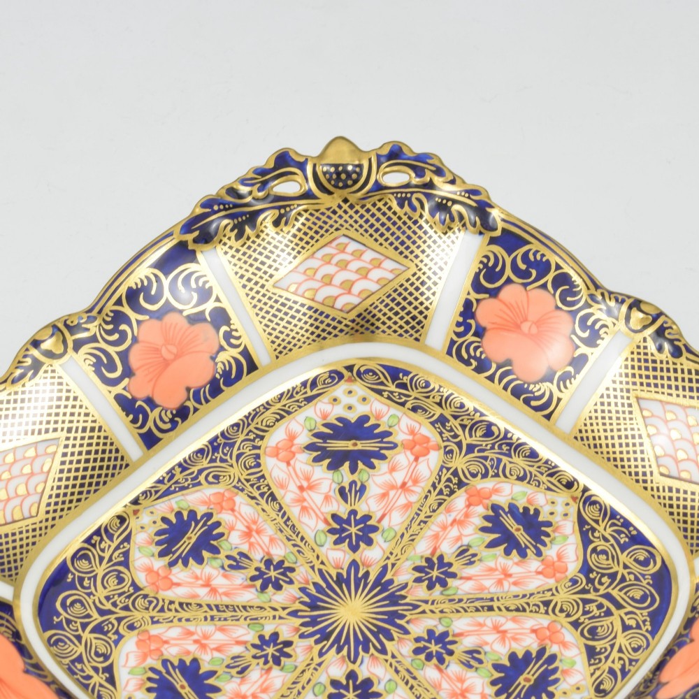 A shallow hexagonal bone china dish decorated in rich cobalt blue, iron red, and gold gilding, featuring pierced side handles and a footed base. View VII