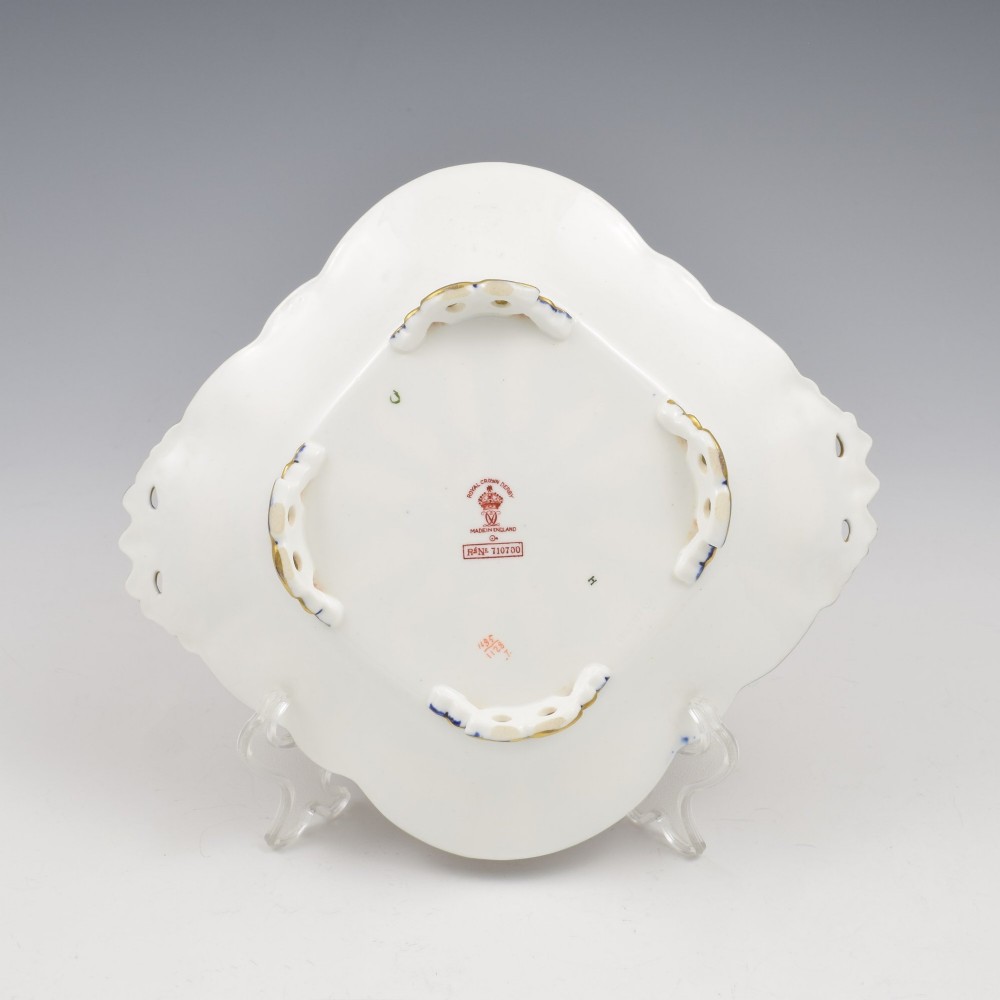 A shallow hexagonal bone china dish decorated in rich cobalt blue, iron red, and gold gilding, featuring pierced side handles and a footed base. View XI