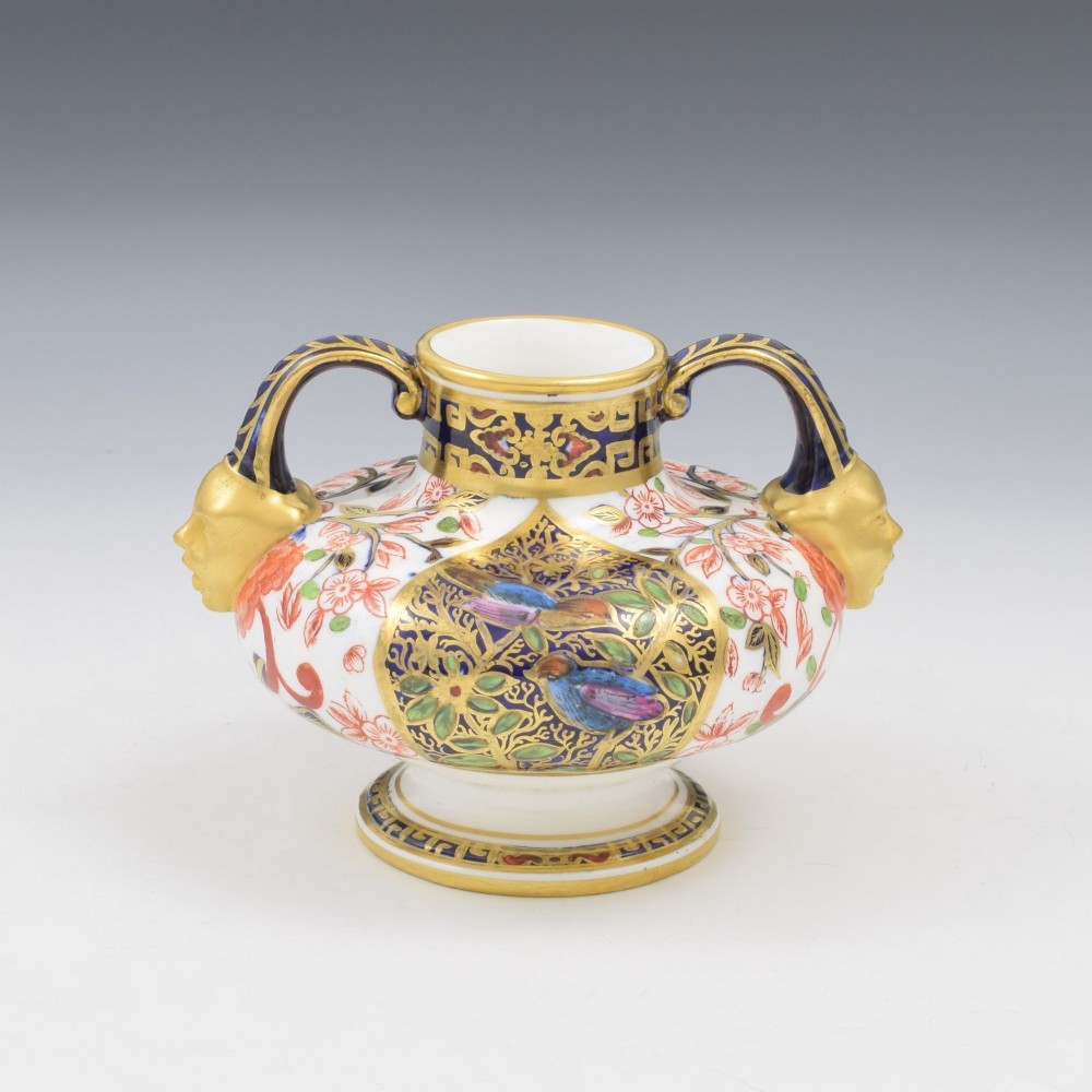 A Victorian Royal Crown Derby porcelain vase featuring twin gilded mask handles, intricate cobalt blue and gold panel decoration, and hand-painted floral motifs.