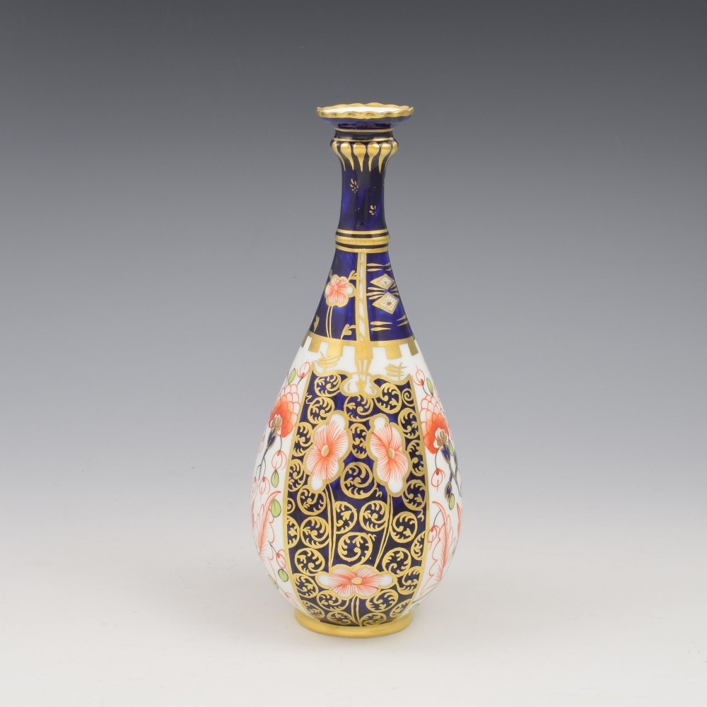 A slender porcelain stem vase featuring cobalt blue, iron red, and gilt hand-painted botanical motifs in the traditional Imari style.