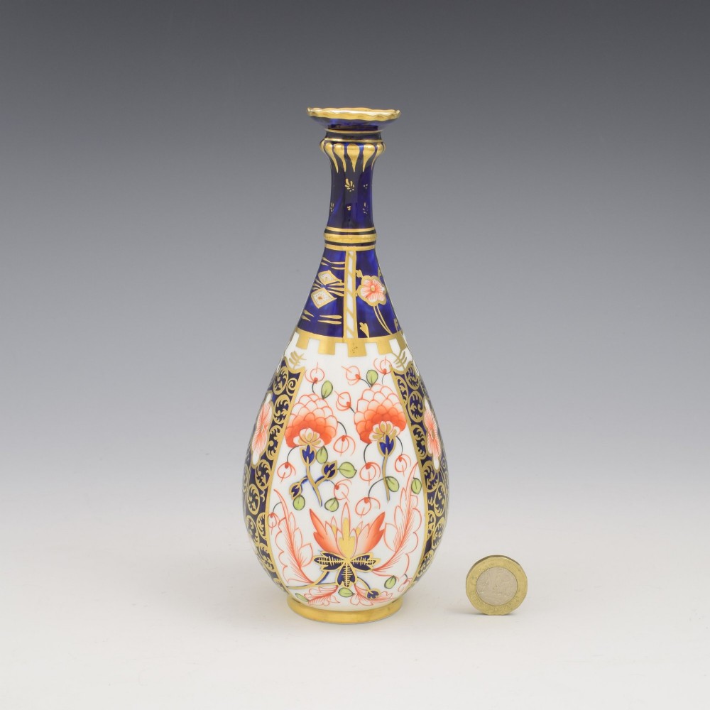 A slender porcelain stem vase featuring cobalt blue, iron red, and gilt hand-painted botanical motifs in the traditional Imari style. View II
