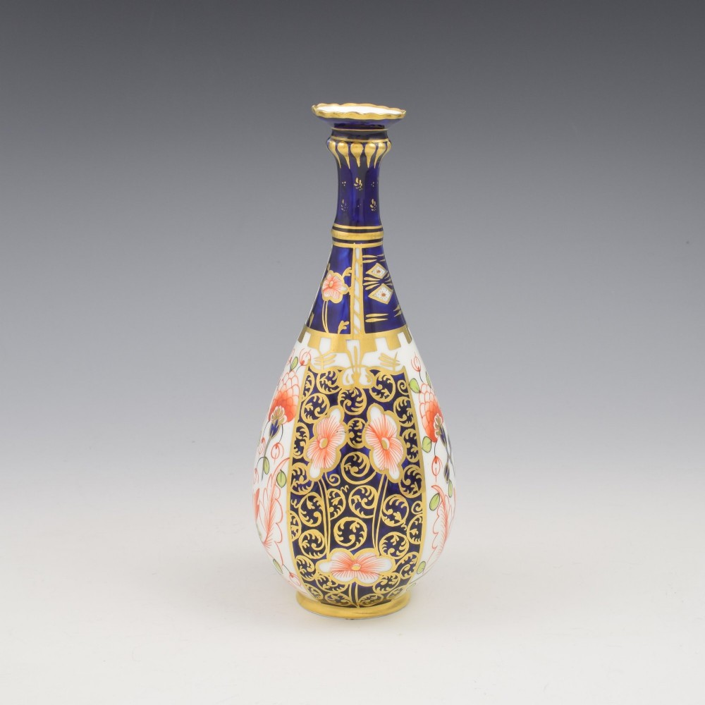 A slender porcelain stem vase featuring cobalt blue, iron red, and gilt hand-painted botanical motifs in the traditional Imari style. View III